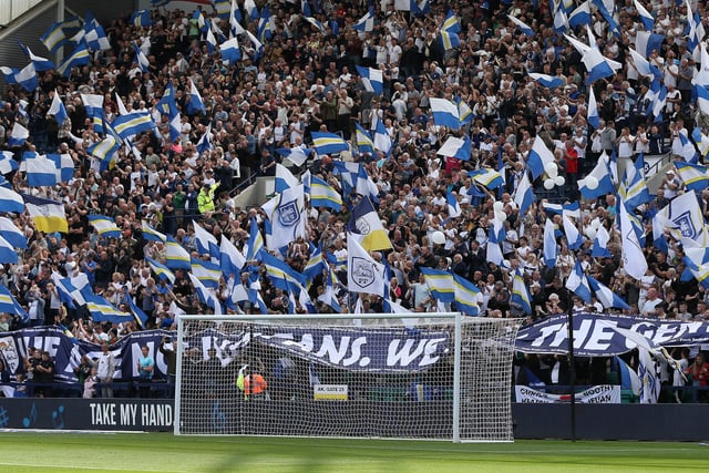 North End supporters waving blue, white and yellow flags behind the goal at Deepdale.